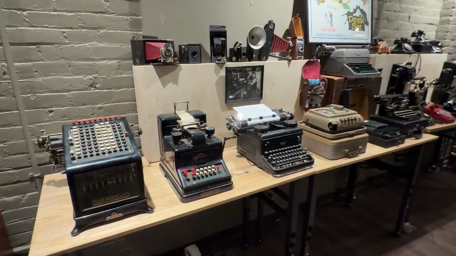 A long table of old typewriters and adding machines